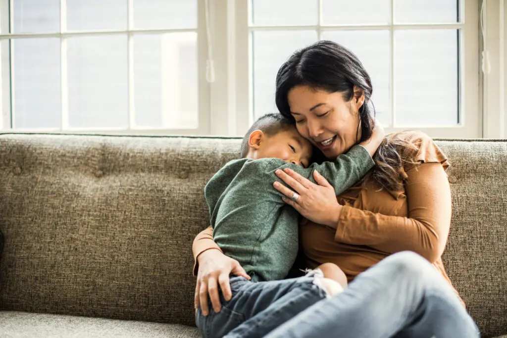Mother hugging son on couch